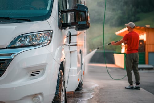 a man washing the exterior of his motorhome as part of his RV maintenance checklist